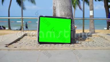 电视站在海滩上。 带有绿色屏幕的电视。 你可以用你想要的镜头或图片代替绿色屏幕。